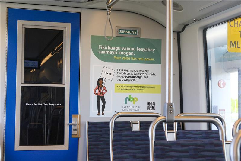 Seattle participatory budgeting poster on interior of bus behind row of seats