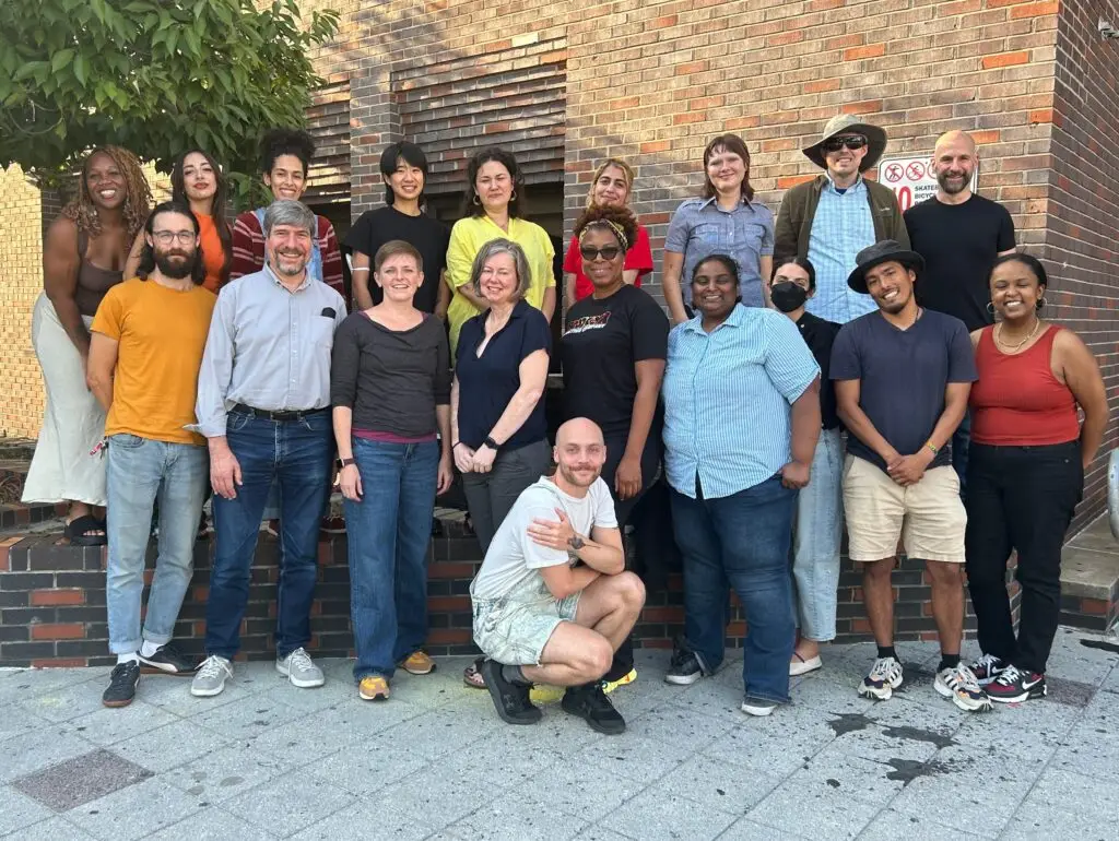A group of people pose outside in front of a brick building