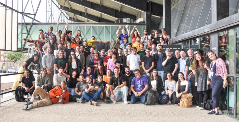 Group photo of conference attendees standing and sitting in several rows in brightly lit indoor space